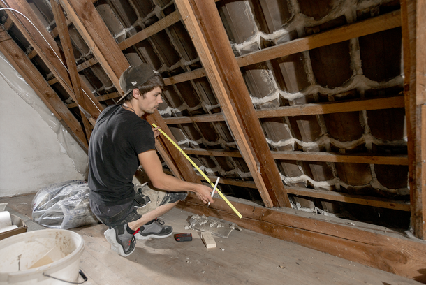 Auf dem Foto ist ein Handwerker beim Dachdämmen abgebildet.