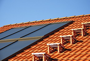 Fördermittel der KfW: Dach mit roten Dachziegeln und Solarzellen